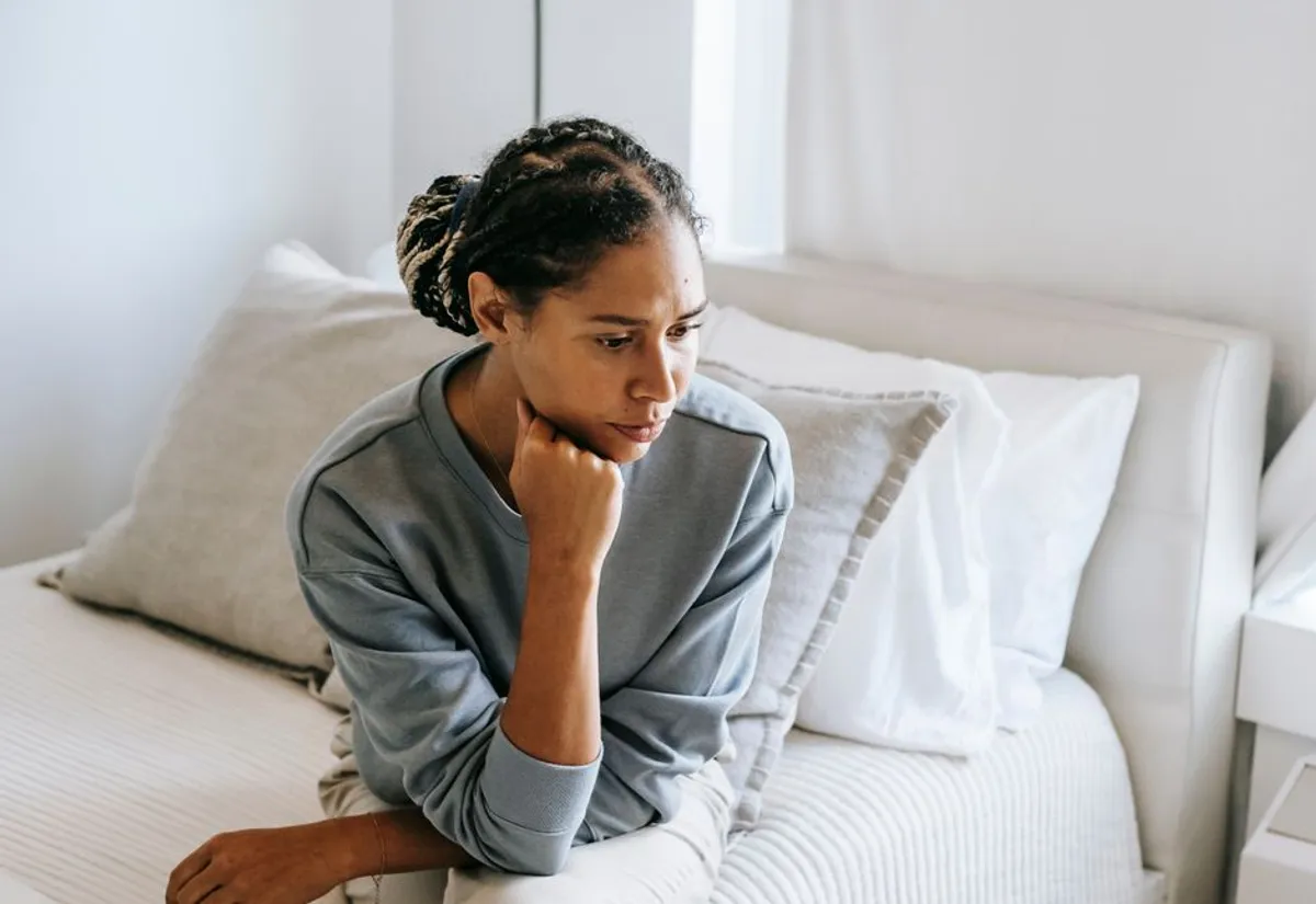 Person sitting quietly at home, looking thoughtful and uncertain