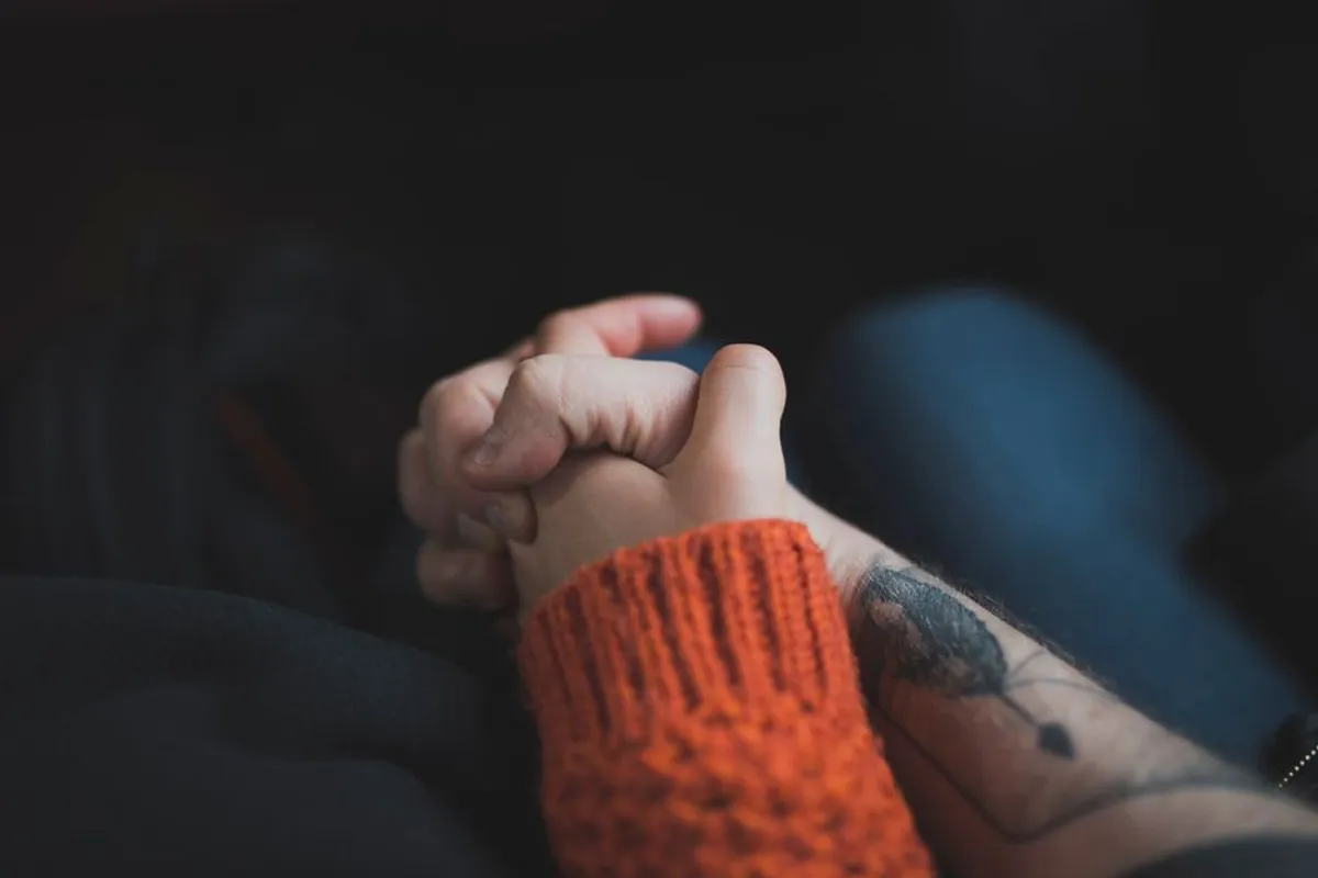 Couple holding hands gently in warm, soft light