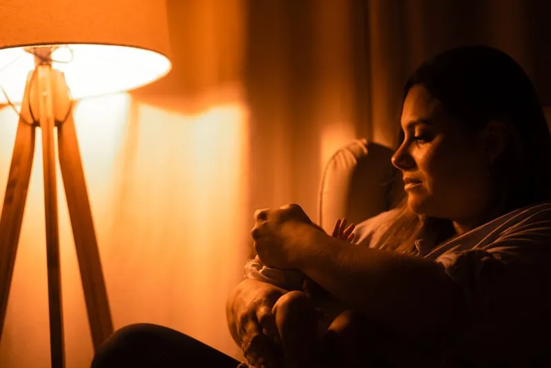 Parent holding a child close in dim light at home at night