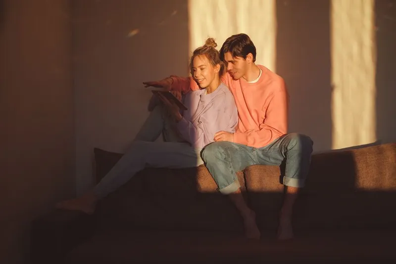 Couple close together on a sofa in warm quiet evening light