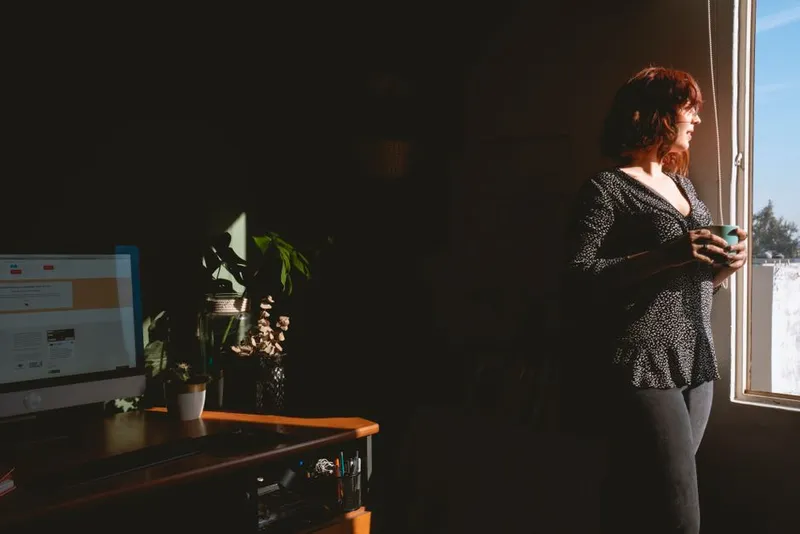 Woman looking thoughtfully out of a window in soft light