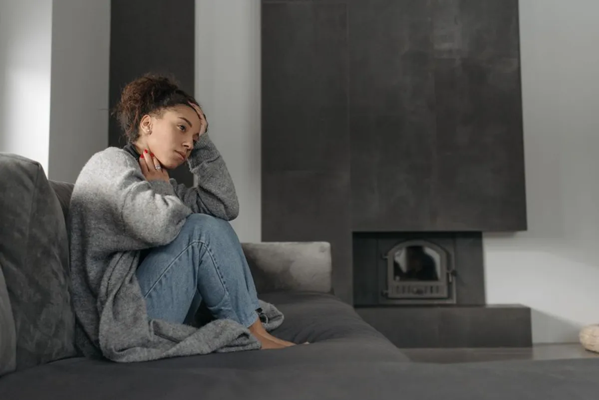 Person sitting alone on a sofa, tired and quiet, in the evening