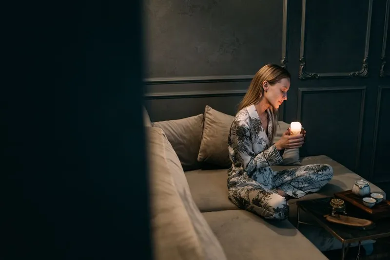 Person sitting quietly and thoughtfully on a sofa in the evening