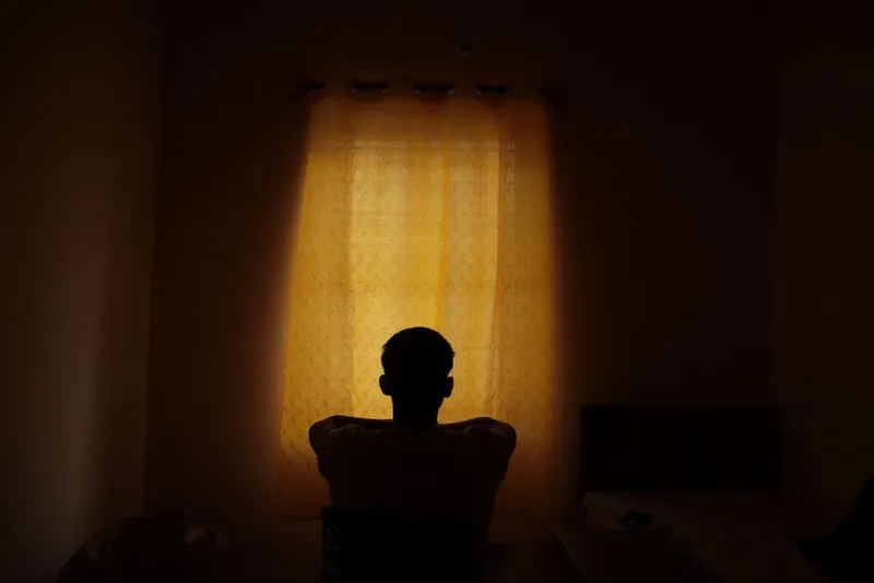 Person sitting quietly alone by a window in soft light