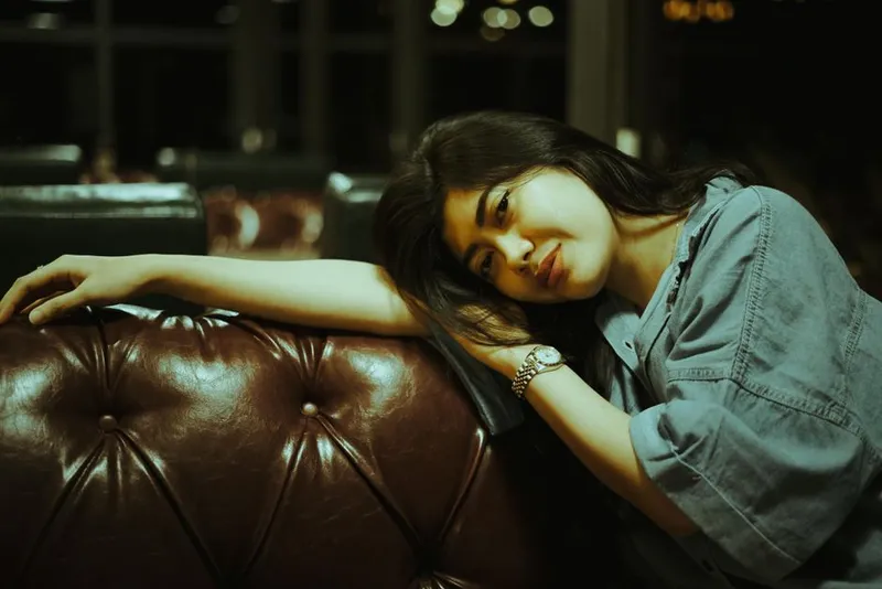 Person sitting alone on a sofa, thoughtful and quiet in warm evening light