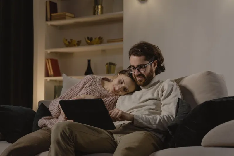 Couple relaxed and comfortable together on a sofa in warm evening light