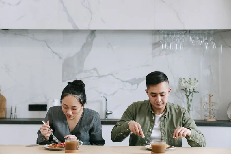 Couple sitting in silence at a kitchen table in the morning